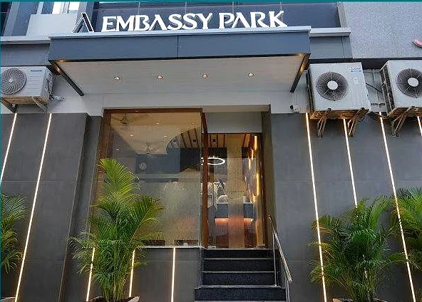 Embassy Park entrance with the illuminated sign and potted palms
